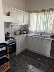 a kitchen with white cabinets and a sink at Villa Theodora 30m from the beach in Egira +7 photos