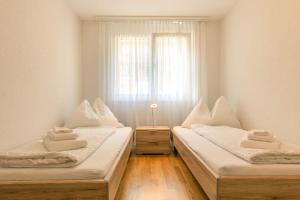 two beds in a room with a window at Moench Apartment - Aare Jungfrau AG in Wilderswil