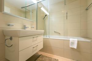 a bathroom with a sink and a tub and a shower at Moench Apartment - Aare Jungfrau AG in Wilderswil