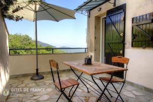 a table and chairs on a balcony with an umbrella at Mezzana in Taglio-Isolaccio