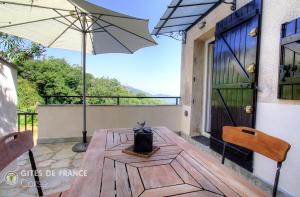 a wooden table with an umbrella on a balcony at Mezzana in Taglio-Isolaccio +18 photos
