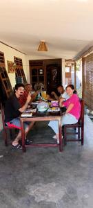 a group of people sitting around a wooden table at Bunaken Jhon Homestay in Manado