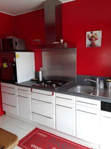 a kitchen with white cabinets and a red wall at Gîte Bourgeois in Isches