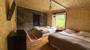 a bedroom with two beds and a stone wall at Ela in Ushguli