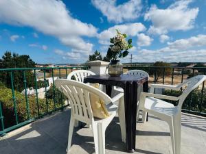 a table with white chairs and a vase with flowers on a balcony at The Yellow Retreat in A dos Cunhados