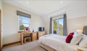 a bedroom with a bed and a desk and windows at No 15 Lomond Castle in Balloch