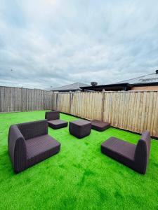 eine Terrasse mit Liegestühlen und Stühlen auf dem Rasen in der Unterkunft Premier Suite with Private Bathroom in Wyndham Vale