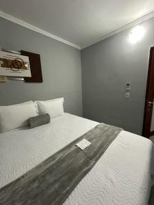 a bedroom with a large white bed with a note on it at Pousada Casa de Naná in Palmas
