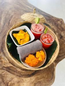 a basket of food on a table with two drinks at Arta Private Villa in Ubud
