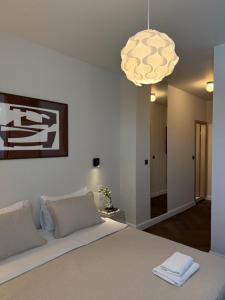 a bedroom with a white bed with a light fixture at Hotel Orion in Vodice