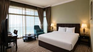 a hotel room with a bed and a chair and a window at Oryx Hotel in Abu Dhabi +26 photos