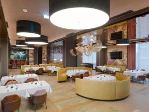a restaurant with white tables and yellow chairs at Mercure Oradea in Oradea