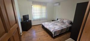 a small bedroom with a bed and a television at Къща за гости ЧЕРИ in Tryavna