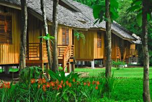 un bâtiment avec des arbres et des fleurs devant lui dans l'établissement La Folie Lodge, à Champassak