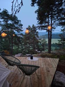 a patio with two chairs and a table on a wooden deck at Halden Glamping in Halden