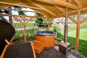 a wooden gazebo with a hot tub and a chair at U Stocha - Jacuzzi & sauna - dom dla 13 osób in Poronin