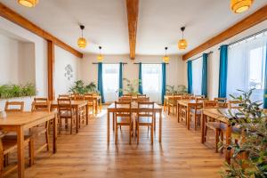 a restaurant with wooden tables and chairs and windows at Chata u kostela in Kořenov