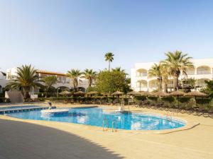 a large swimming pool with chairs and palm trees at Ona Village Cala d'Or in Cala d´Or