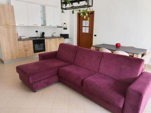 a purple couch in a living room with a kitchen at Casa Moscati in Avellino