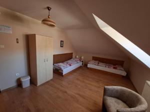 a attic room with two beds and a chair at Pension Chalupka l with a panoramic view of Spiš Castle in Spišské Podhradie