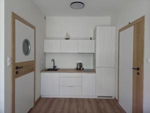 a kitchen with white cabinets and a sink next to a door at Via Mare in Jantar