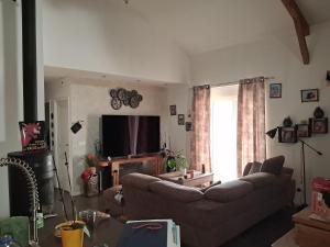 a living room with a couch and a television at Chambre chez l'habitant "lou Castanier" in Cayrols