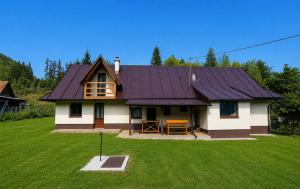 a house with a purple roof on a green field at Chata Huta in Muránska Huta +5 photos