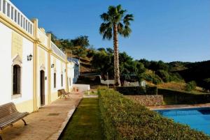 a building with a palm tree next to a swimming pool at Herdade Da Corte in Tavira