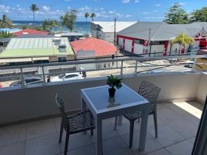 a table and chairs on a balcony with a view of a boat at La Kaz Saint-Annaise in Sainte-Anne