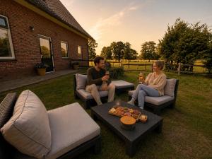 a man and a woman sitting on chairs in a yard at Woonboerderij Markelo in Markelo
