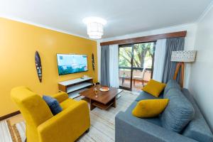 a living room with a blue couch and yellow chairs at Heri Heights Hotel Apartments, SureStay Collection by Best Western in Nairobi