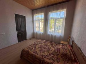 a bedroom with a bed and two windows at Cozy home racha in Ambrolauri