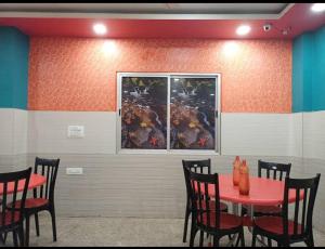 a dining room with a red table and chairs at Shravan Hotel in Rāmgarh +6 photos