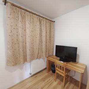 a room with a television and a table and a curtain at Anna Vendégház Tarcal in Tarcal