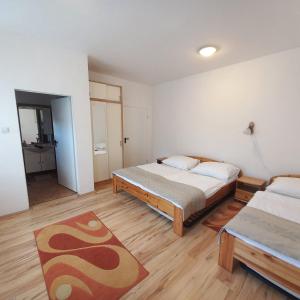 a bedroom with two beds and a rug at Anna Vendégház Tarcal in Tarcal