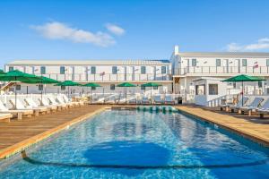a pool with chairs and umbrellas in front of a building at Offshore Spa & Residences in Montauk