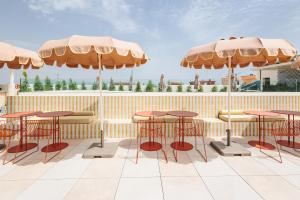 a patio with tables and chairs and umbrellas at Intelier Malvarrosa Plaza in Valencia