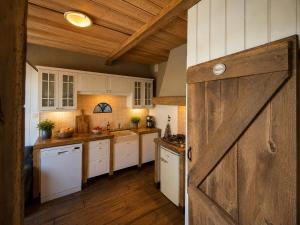 a kitchen with white cabinets and a wooden door at Woonboerderij Markelo in Markelo