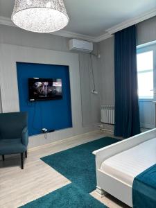 a bedroom with a bed and a tv on a blue wall at Апартаменты на набережной 15 этаж in Astana