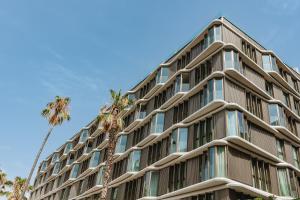 a tall building with a palm tree in front of it at Intelier Malvarrosa Plaza in Valencia