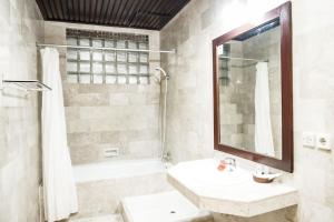 a white bathroom with a sink and a mirror at Melasti Kuta Beach Hotel & Spa in Kuta