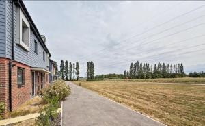 a house with a road next to a field at Sweet Haven in Sittingbourne