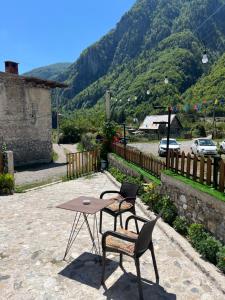 a table and two chairs on a patio with a mountain at Guest House Shtëpiza Theth in Theth +57 photos