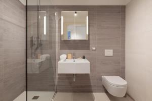 a bathroom with a sink and a toilet and a shower at Portopiccolo Apartments Deluxe in Sistiana