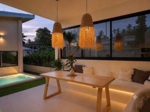 a living room with a table and a pool at La Caza Sowana in Ko Phangan