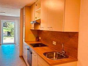 a kitchen with a stainless steel sink and wooden cabinets at Ferienwohnung Mondseeblick in Tiefgraben