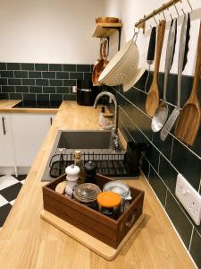 a kitchen sink with a wooden tray on the counter at Little B - Artist owned boutique apartment near Southsea beach in Portsmouth