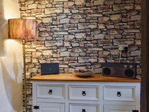 a stone wall with a table with a laptop and a lamp at Byways in Cartmel