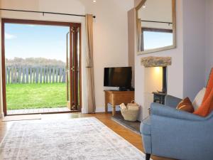 a living room with a couch and a tv and a sliding glass door at Beudy Newydd - Uk50959 in Llanllechid