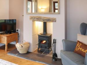 a wood stove in a living room with a couch at Beudy Newydd - Uk50959 in Llanllechid